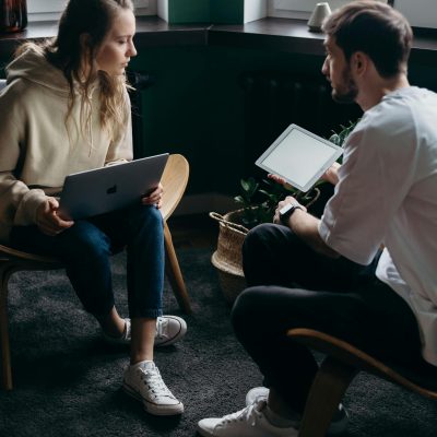 Photo of Couple Talking While Holding Laptop and Ipad